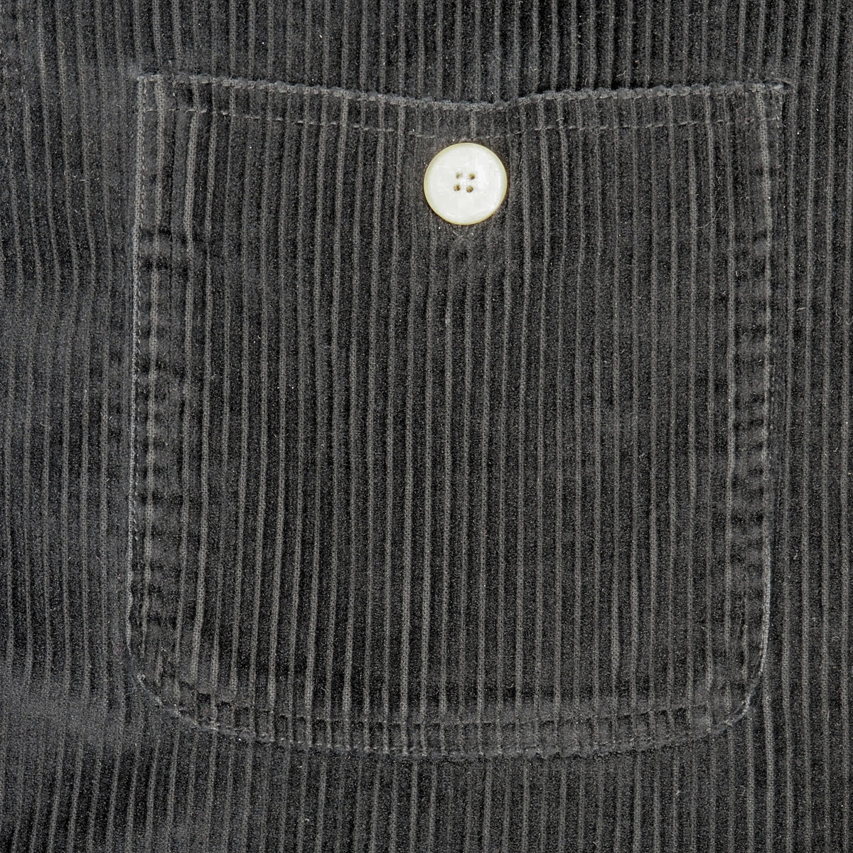 Close-up of a dark gray corduroy pocket with a single light coloured button, showing the ribbed fabric texture in detail.