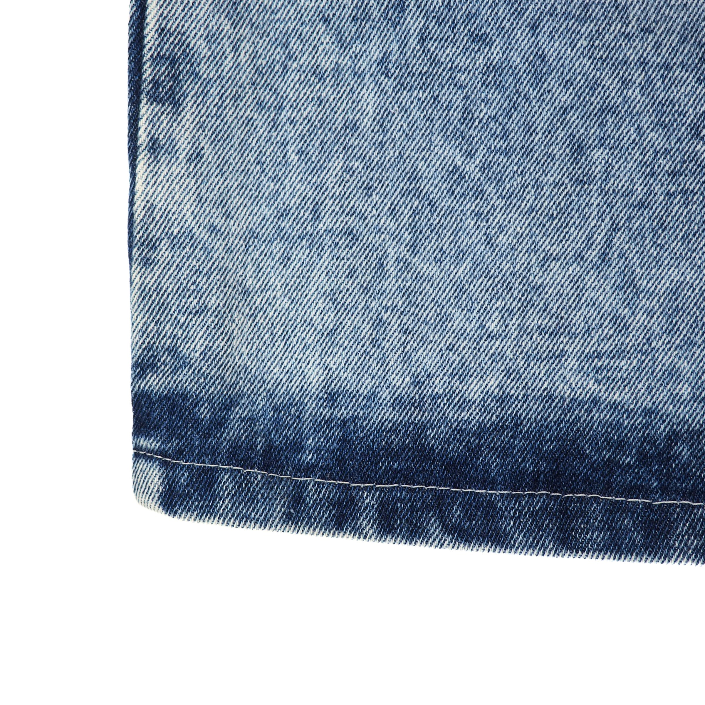Close-up of blue denim fabric seam with a white background