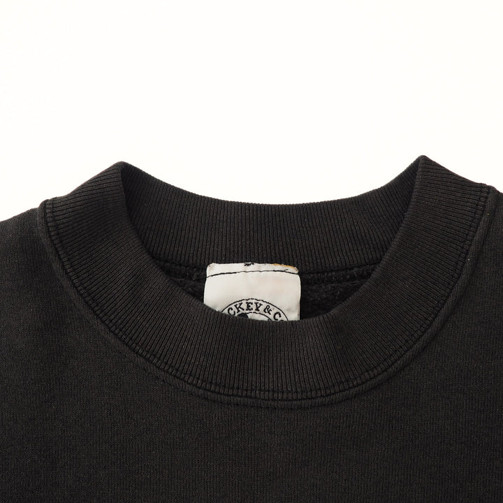 Close-up of a black sweater collar with a brand label on a white background