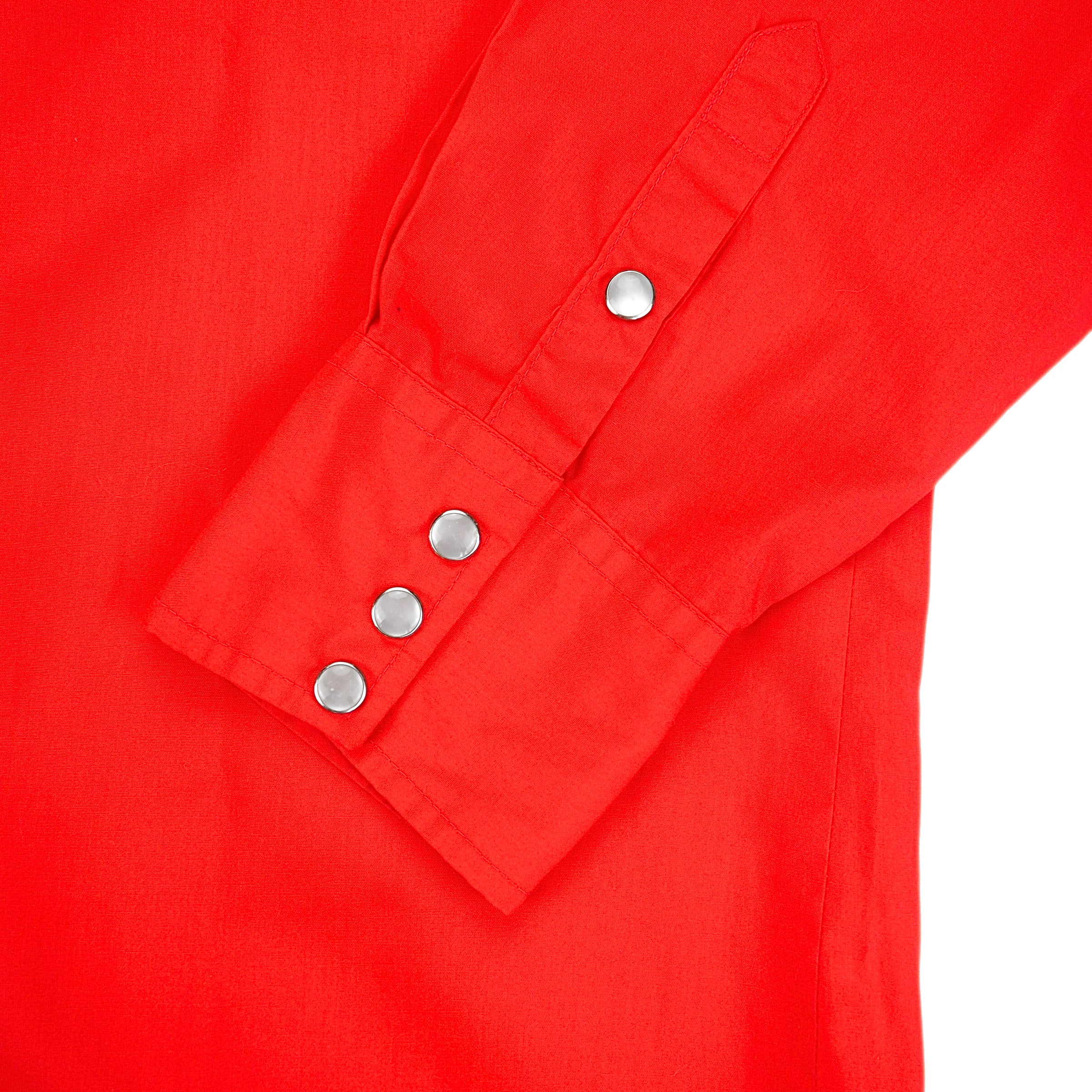 Close up of pearl snap buttons of the cuff of a red dress shirt.