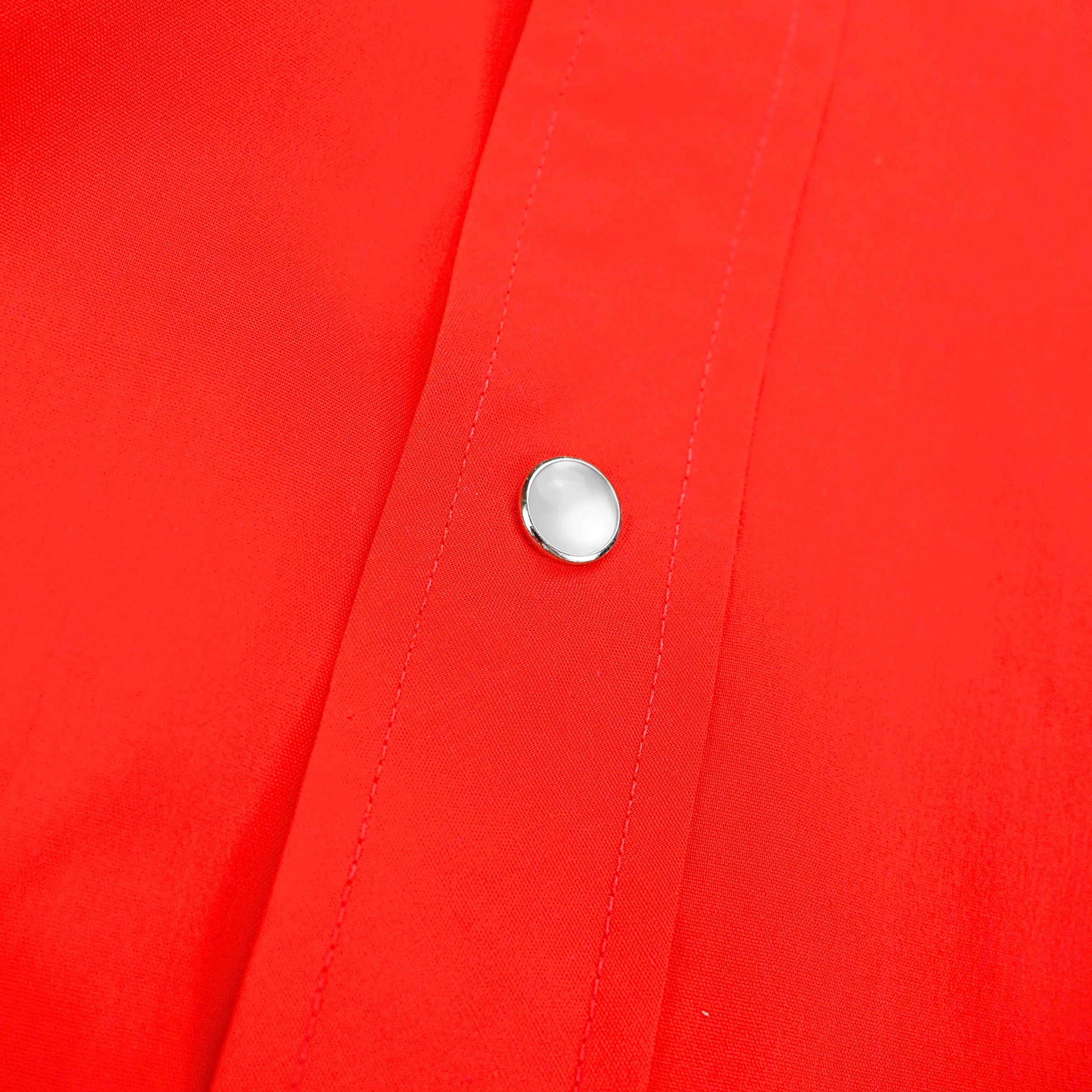 Close up of pearl snap button on a red shirt.