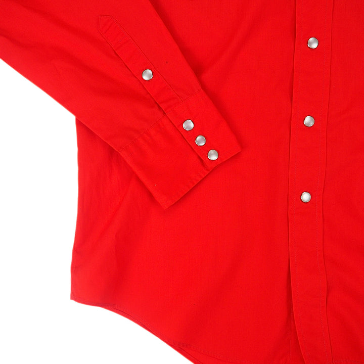 Close up of pearl snap buttons of the cuff of a red dress shirt.