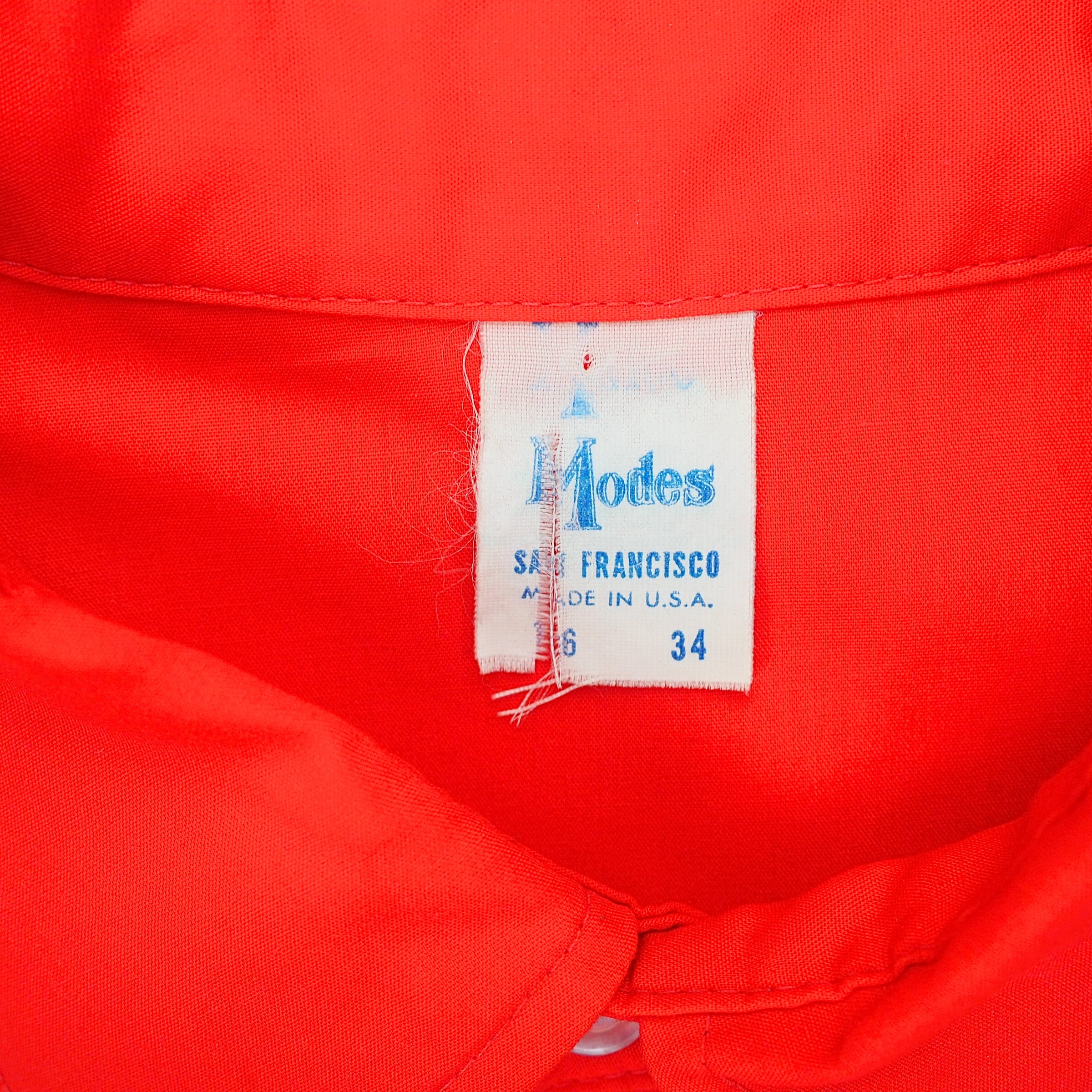 Close up of a label of a red shirt with the brand name 'Modes' 