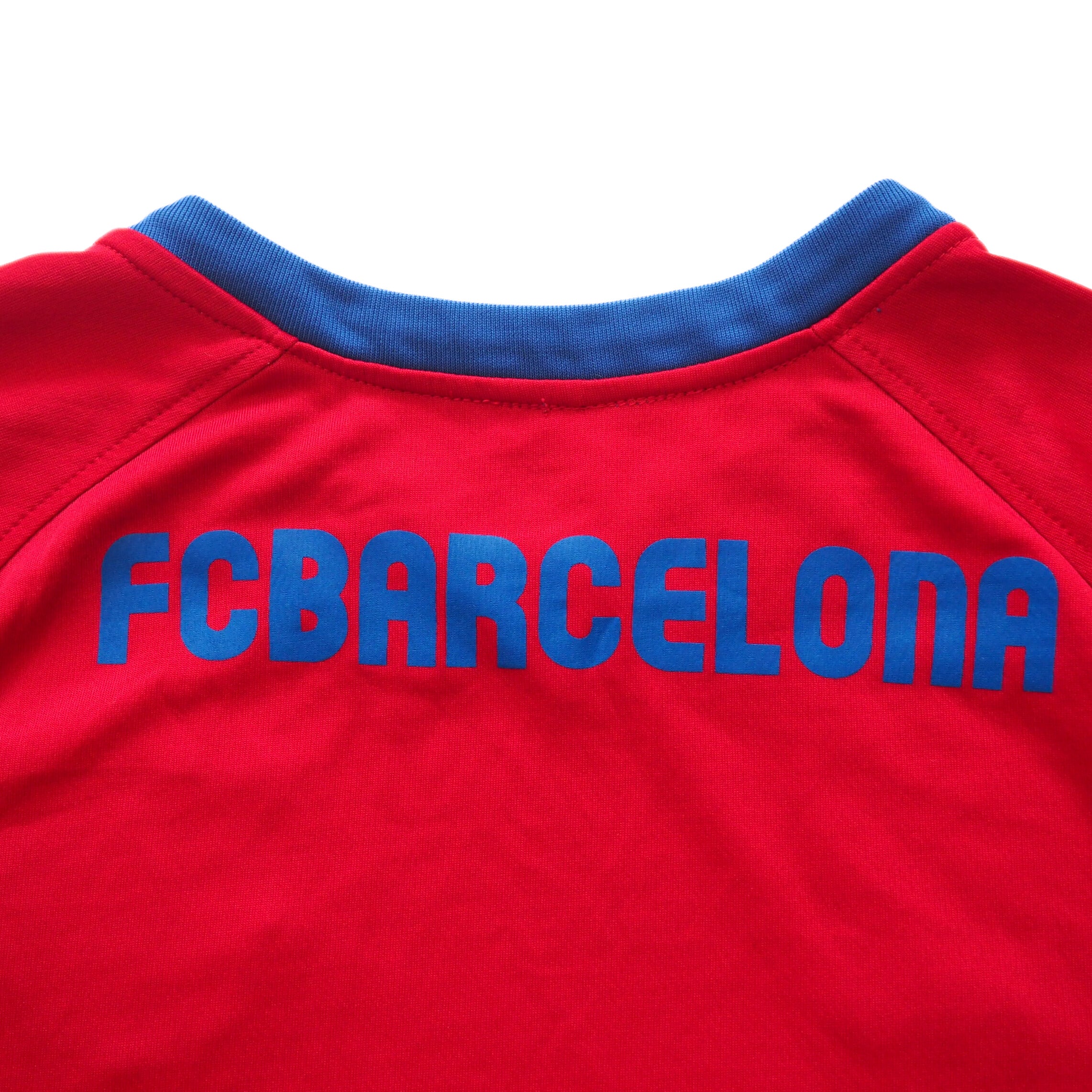 Back collar detail of a red jersey with blue 'FC Barcelona' text on a white background