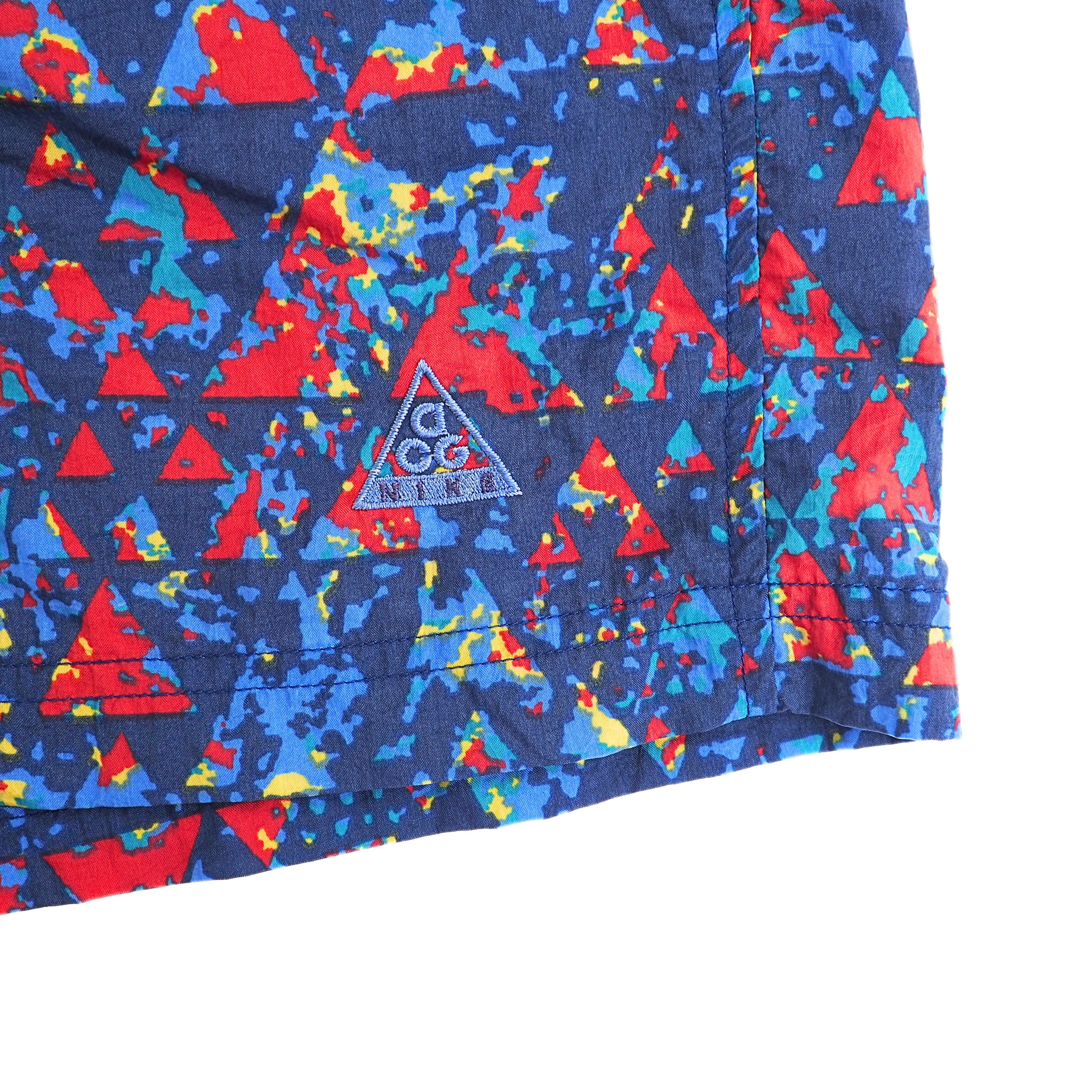 Colorful geometric patterned fabric with a 'Nike ACG' logo on a white background