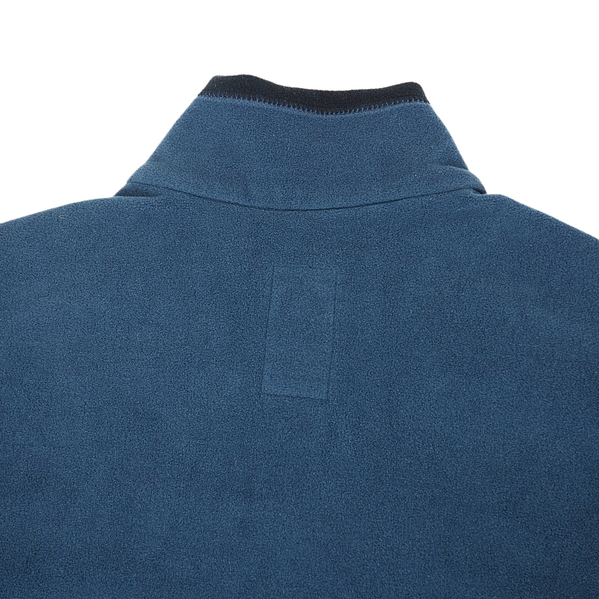 Close-up of the back of a blue fleece pullover jacket, showing a ribbed dark collar and a rectangular patch on the upper back, set against a plain white background.