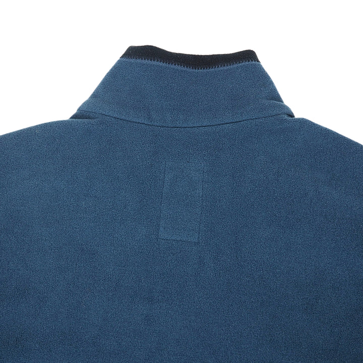 Close-up of the back of a blue fleece pullover jacket, showing a ribbed dark collar and a rectangular patch on the upper back, set against a plain white background.