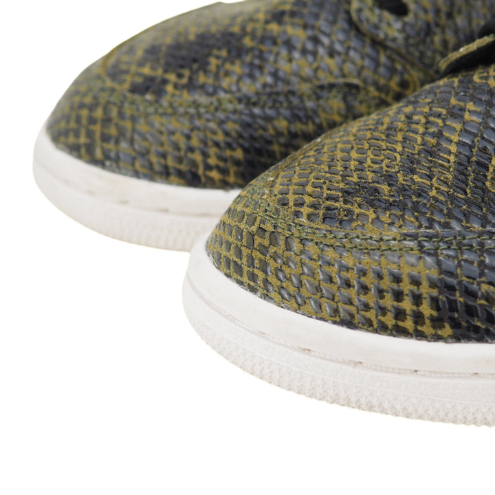 Close-up of green and black snakeskin patterned shoes with white soles on a white background
