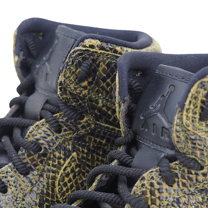 Close-up of a pair of black and green  snakeskin high-top sneakers with embossed 'Air Jordan' branding on the tongue.