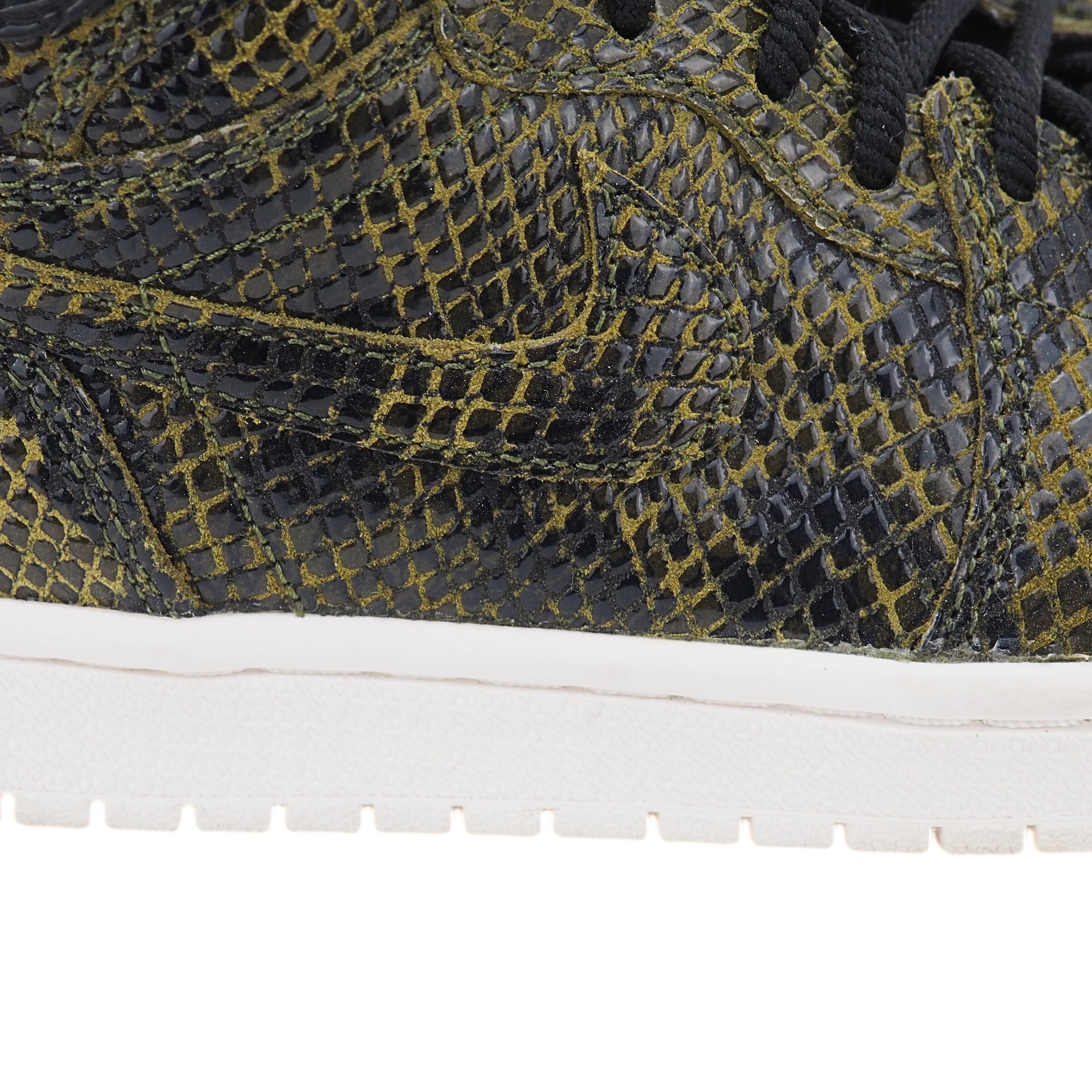 Close-up of the outside of a snakeskin sneaker with a Nike Swoosh on the side and a white midsole.