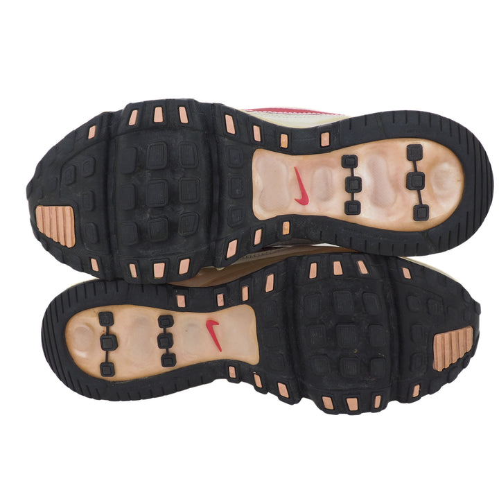 Black and pink soles of a pair of Nike running shoes with a swoosh logo on a white background