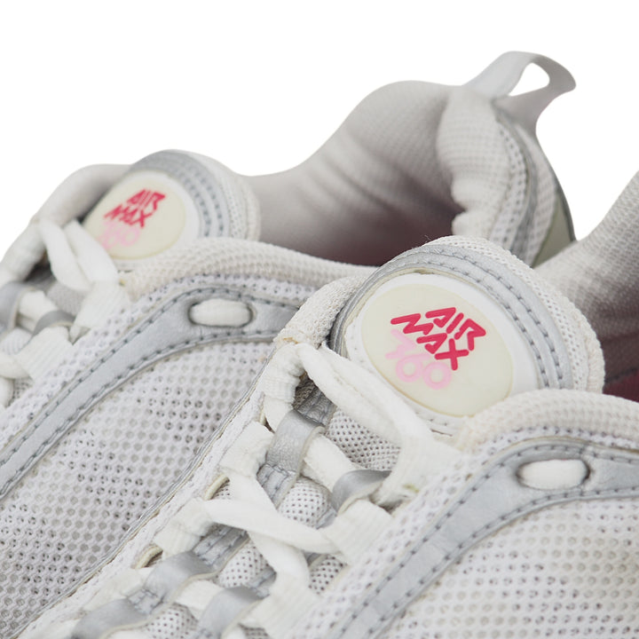 Close-up of white sneakers with pink and red logo on the tongue against a white background