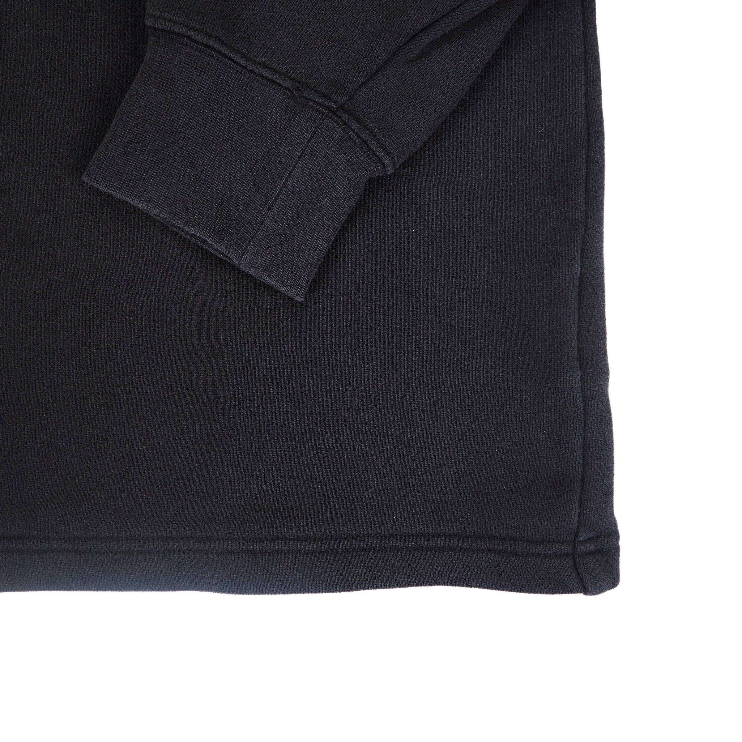 A black sweater sleeve cuff folded across the body on a white background