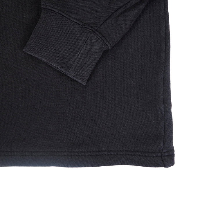 A black sweater sleeve cuff folded across the body on a white background