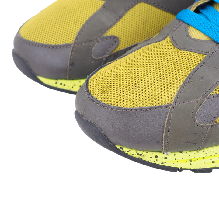 Yellow and gray athletic shoes with blue laces on a white background