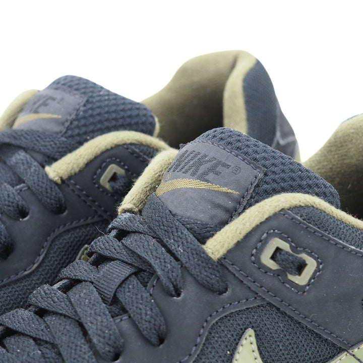 Close-up of a pair of black and green sneakers with Nike logo on the tongue.