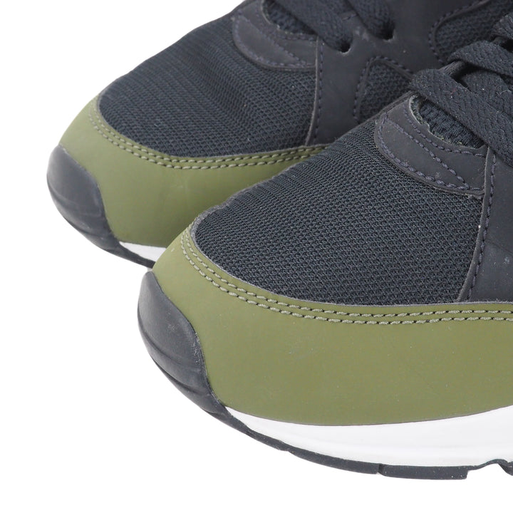 Close up of the toe area of a pair of black and green sneakers on a white background