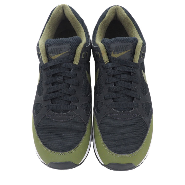 Pair of black and green Nike sneakers on a white background