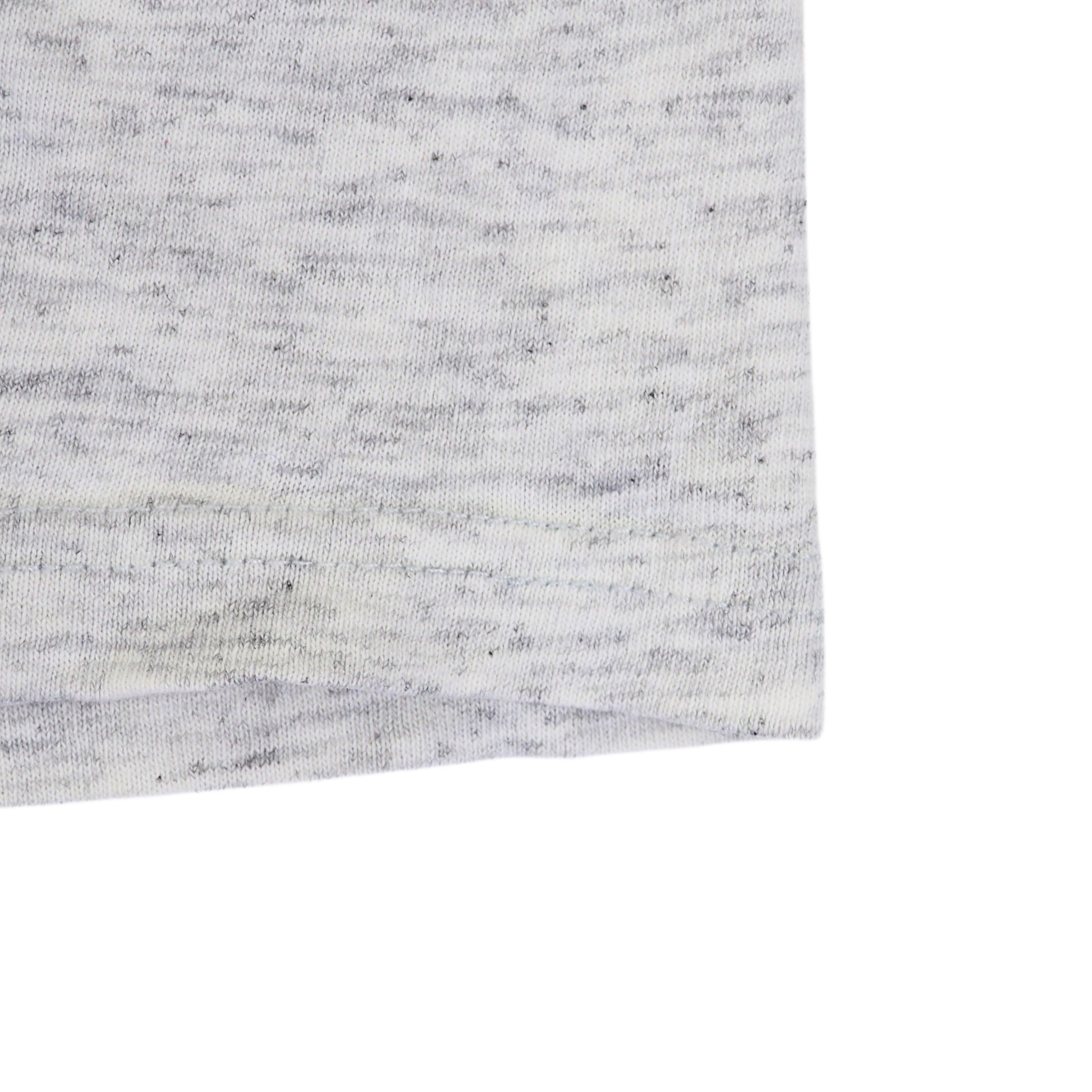 Close up of the hem of a heathered grey t-shirt on a white background