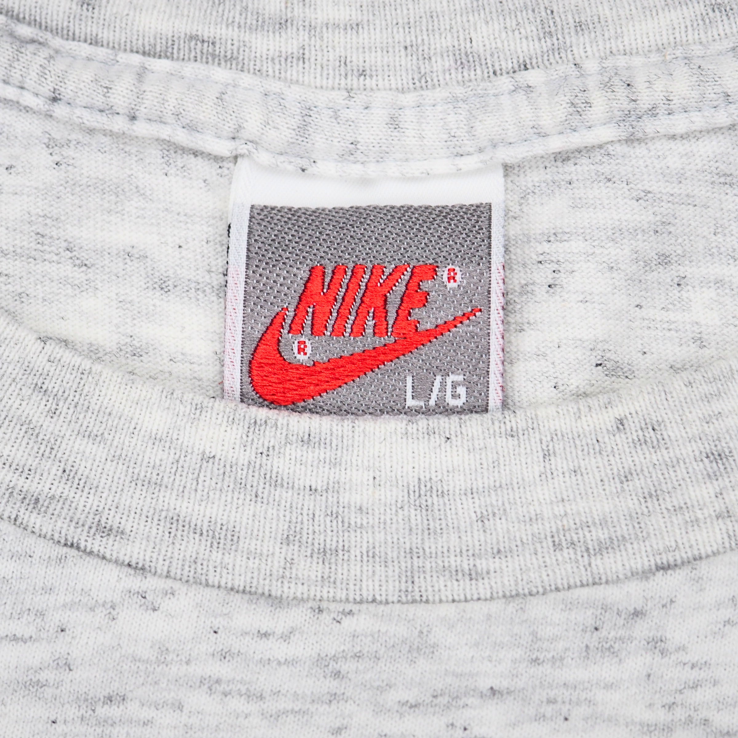 Close up of a vintage Nike brand tag on the inside collar of a grey t-shirt