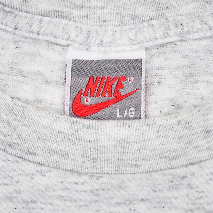 Close up of a vintage Nike brand tag on the inside collar of a grey t-shirt