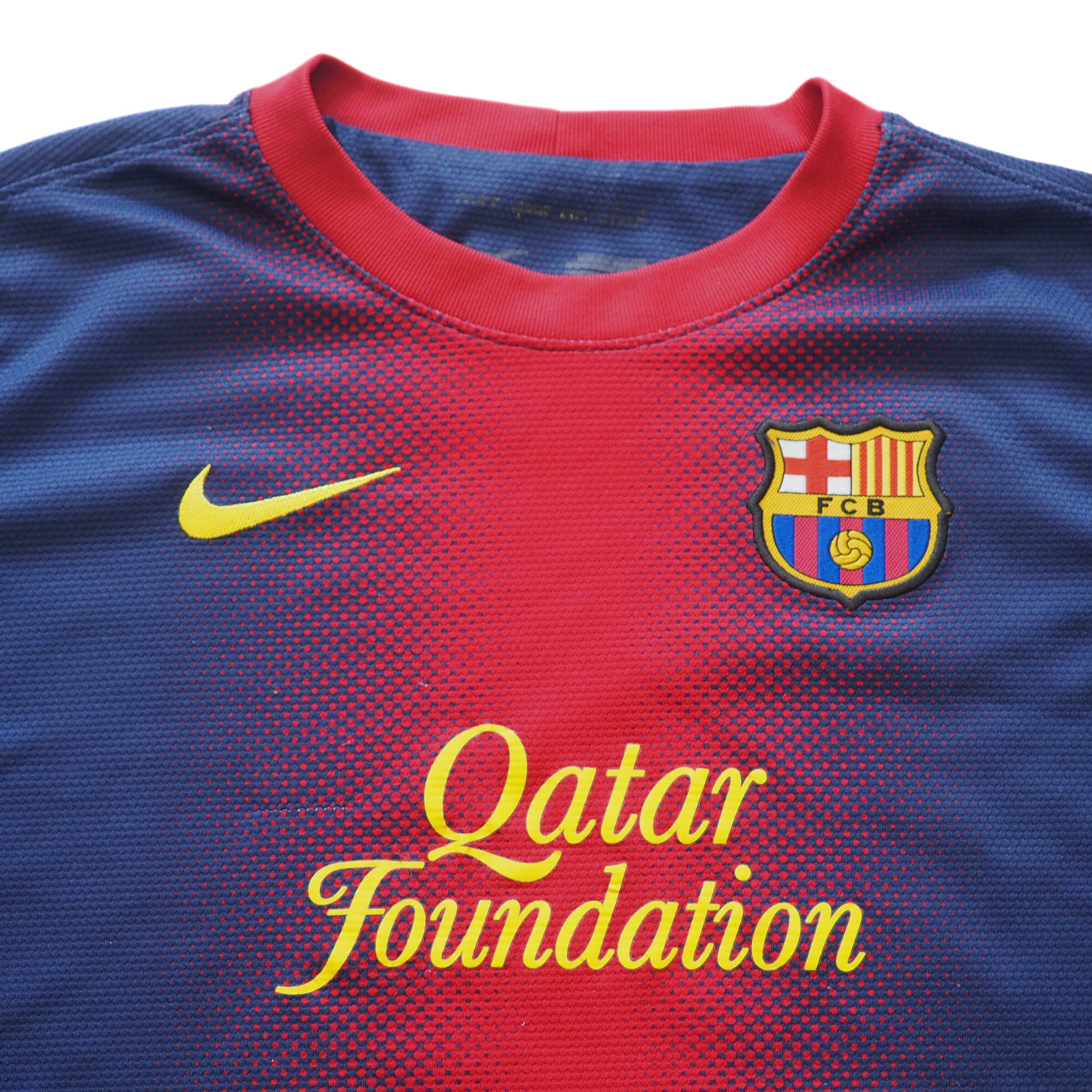 Close-up detail of chest and collar of a blue and red soccer jersey with a Nike logo and FC Barcelona emblem.