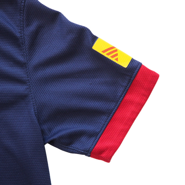 Close-up of a blue soccer jersey sleeve with red cuff and a yellow logo on a white background
