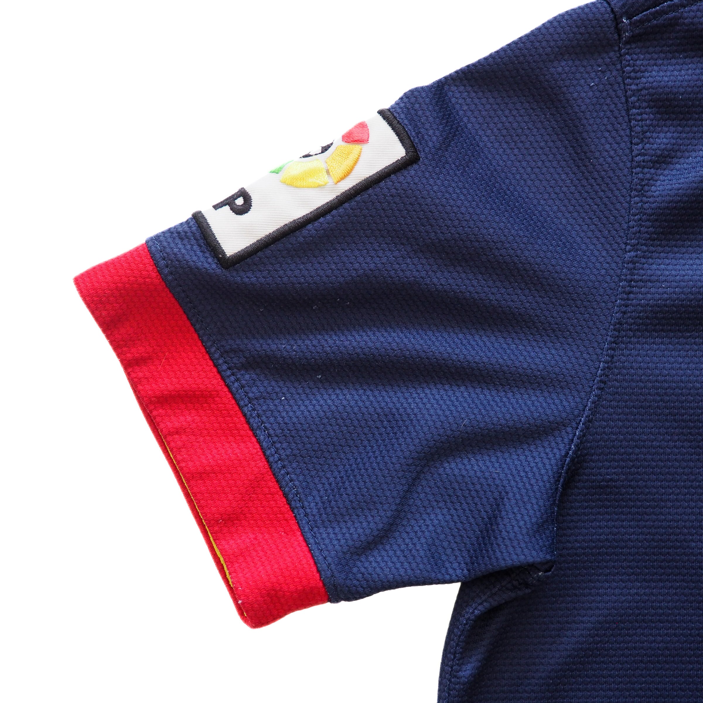 Close-up of a blue soccer jersey with red trim and a brand logo on the sleeve.