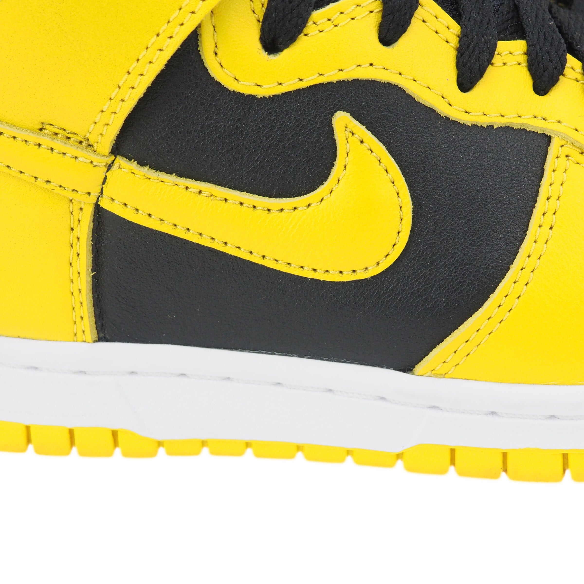 Close-up of a yellow and black Nike Dunk sneaker with a prominent Nike Swoosh logo.
