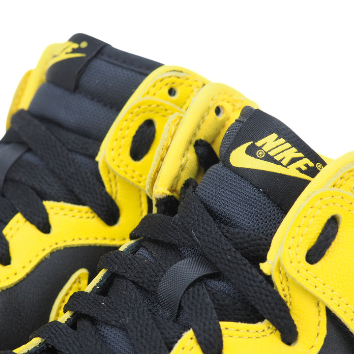 Close-up of black and yellow Nike sneakers with black laces and a Nike logo on the tongue.