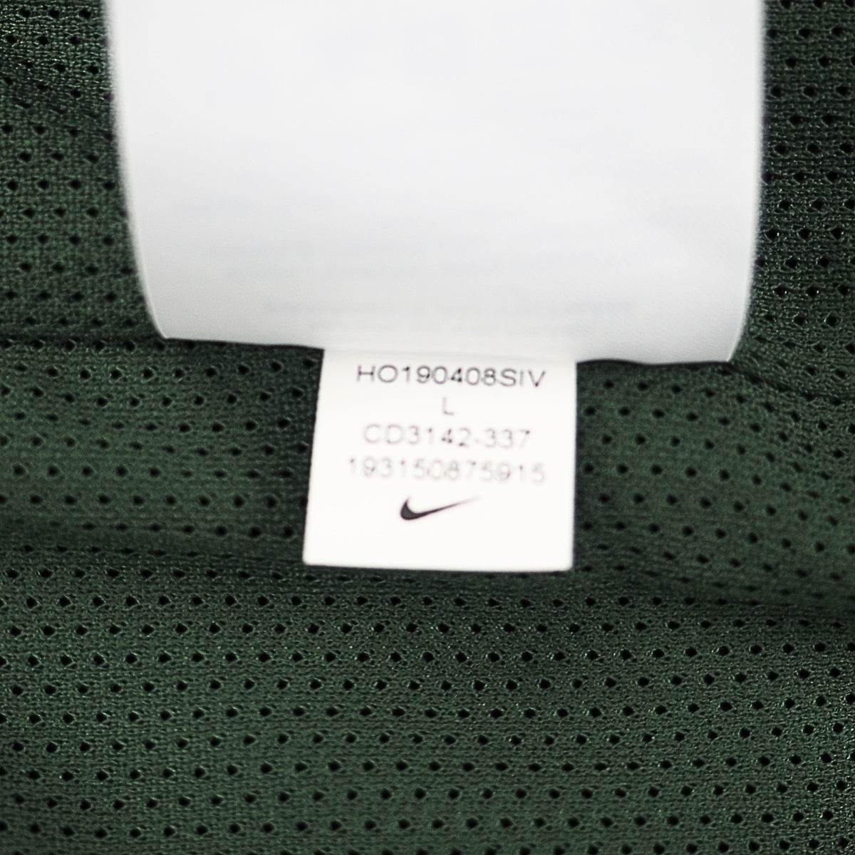 Close-up of a dark green mesh garment tag with a white Nike swoosh logo and printed size information.