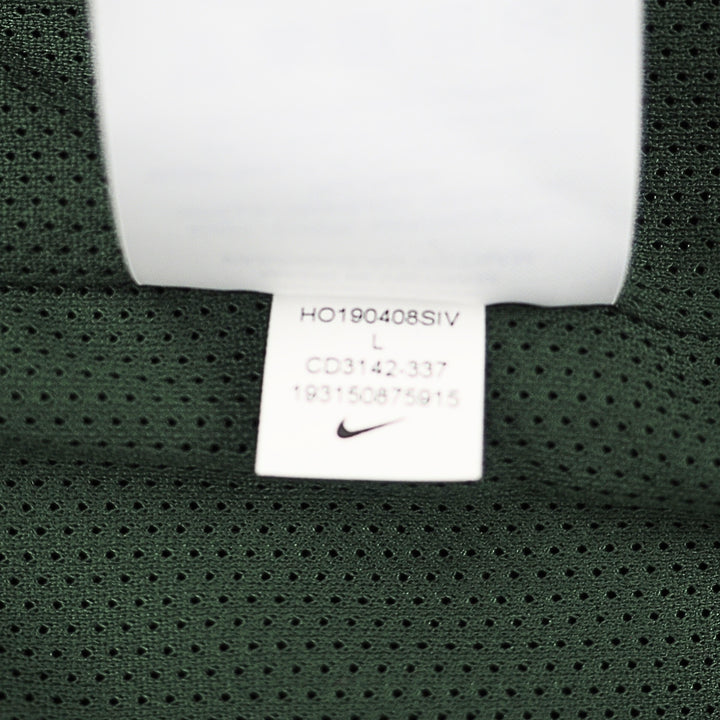 Close-up of a dark green mesh garment tag with a white Nike swoosh logo and printed size information.