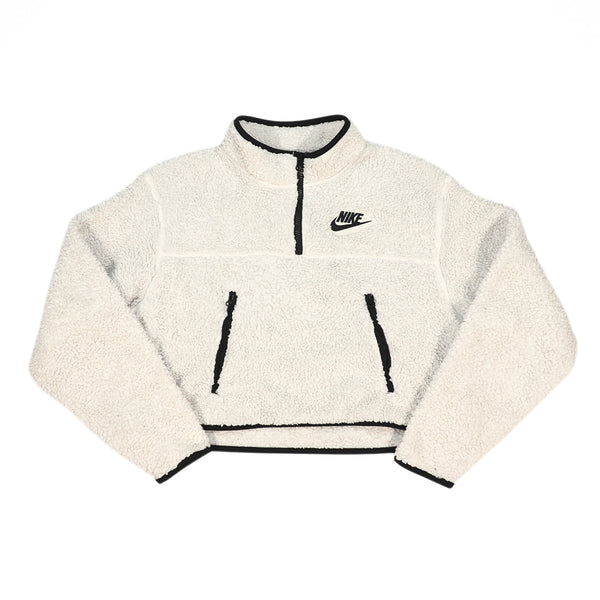 A cream-colored fleece pullover jacket with black trim, featuring a half-zip neckline, two front zip pockets, and a black Nike logo on the left chest, displayed on a solid white background.