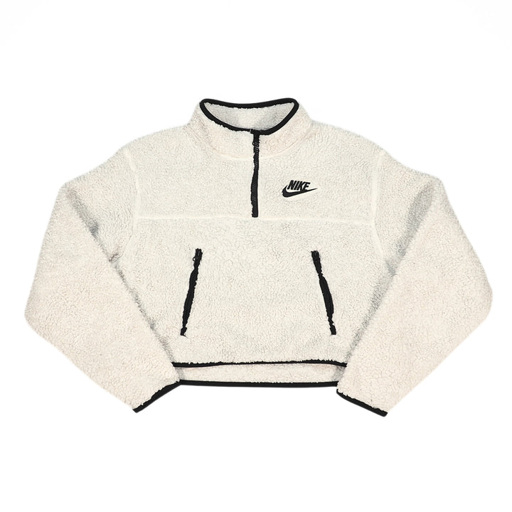 A cream-colored fleece pullover jacket with black trim, featuring a half-zip neckline, two front zip pockets, and a black Nike logo on the left chest, displayed on a solid white background.