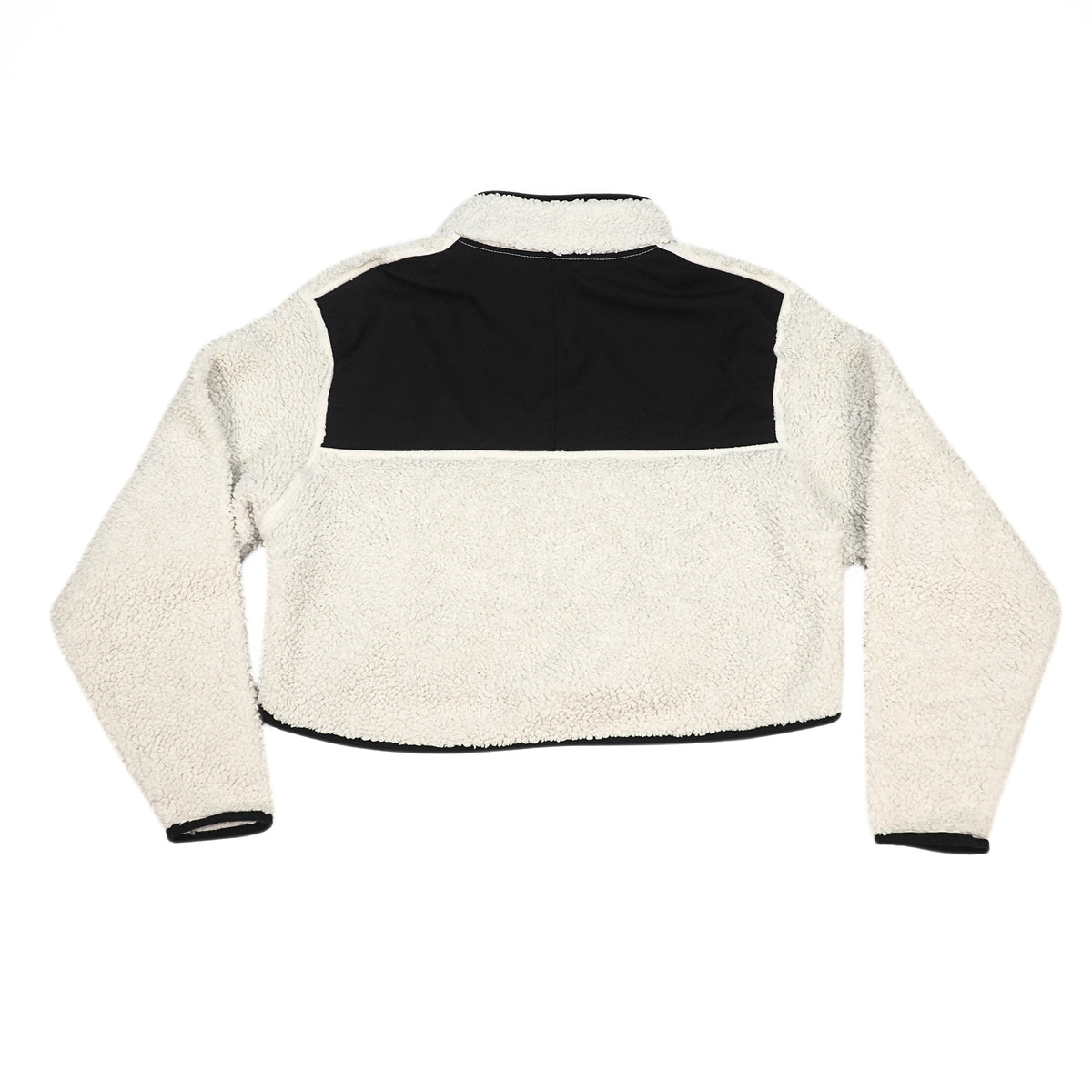A cropped sherpa fleece jacket with a high collar, featuring a black yoke panel across the upper chest and shoulders, with long cream-colored sleeves and black ribbed cuffs and hem.