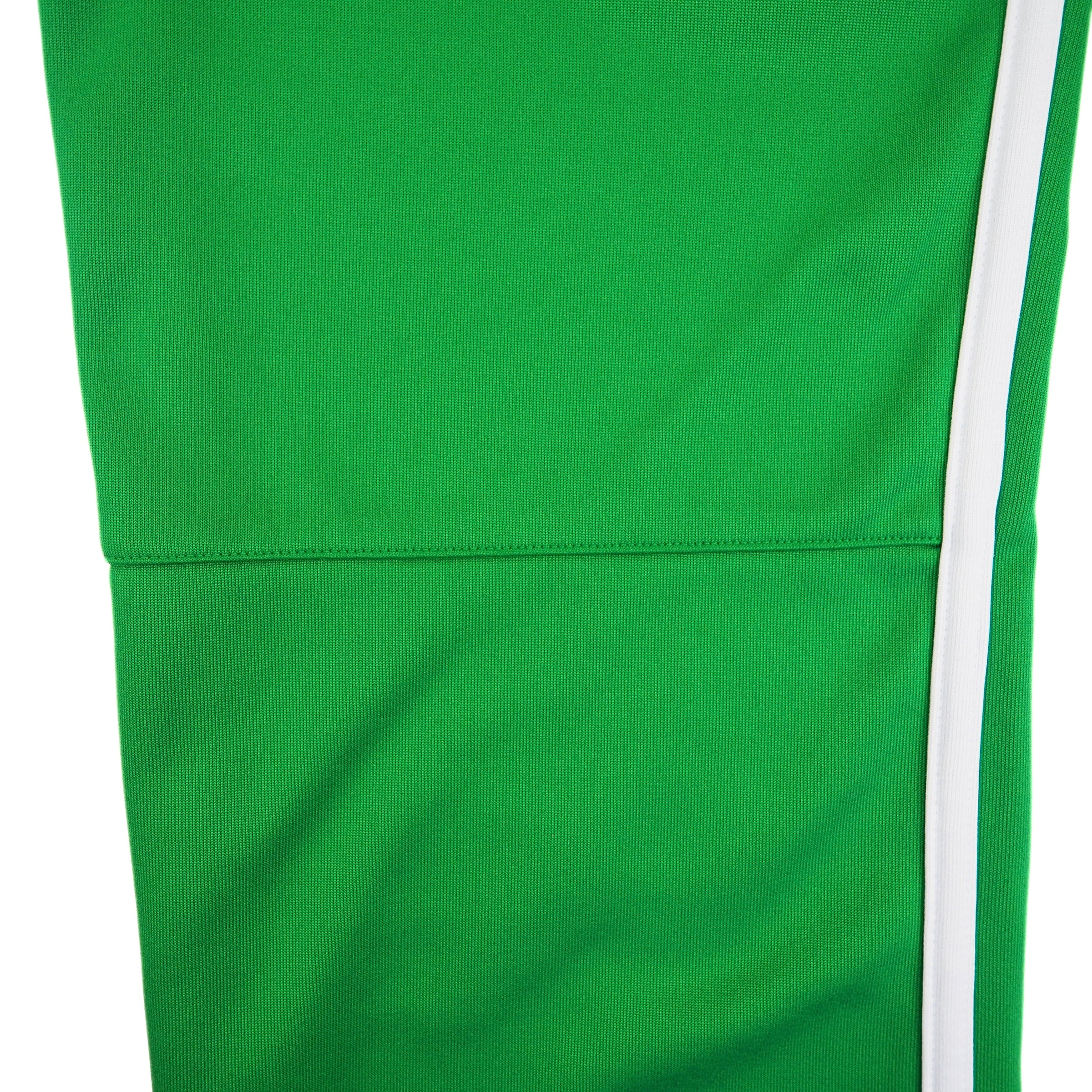 Pant leg detail of a pair of green Nike track pants with white stripes on a white background