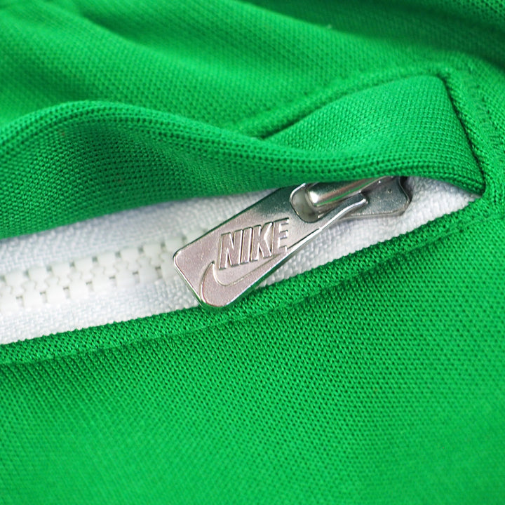 Close-up of a green Nike track pants pocket with a silver branded Nike zipper