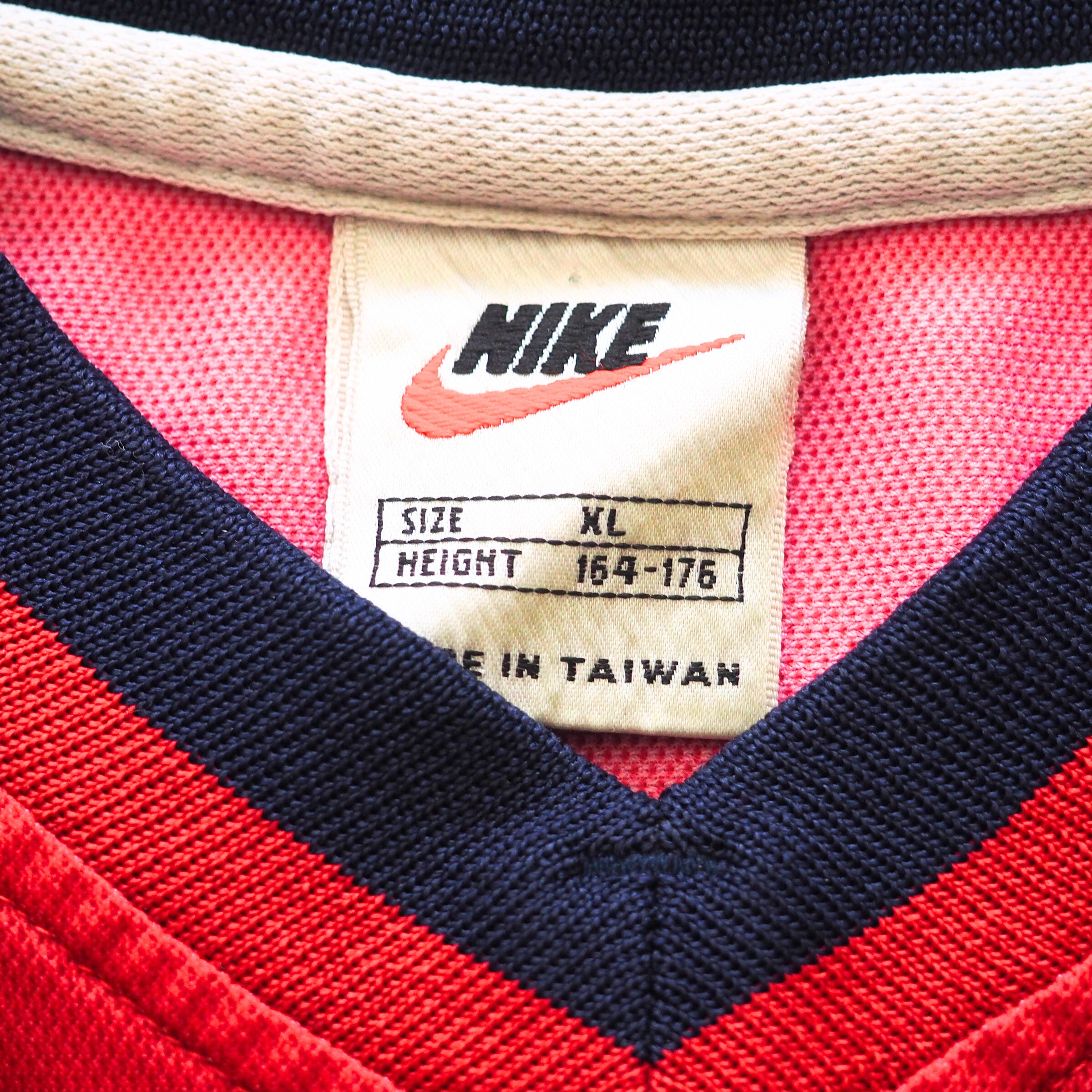 Close-up of a vintage Nike label on a red and navy sports jersey.