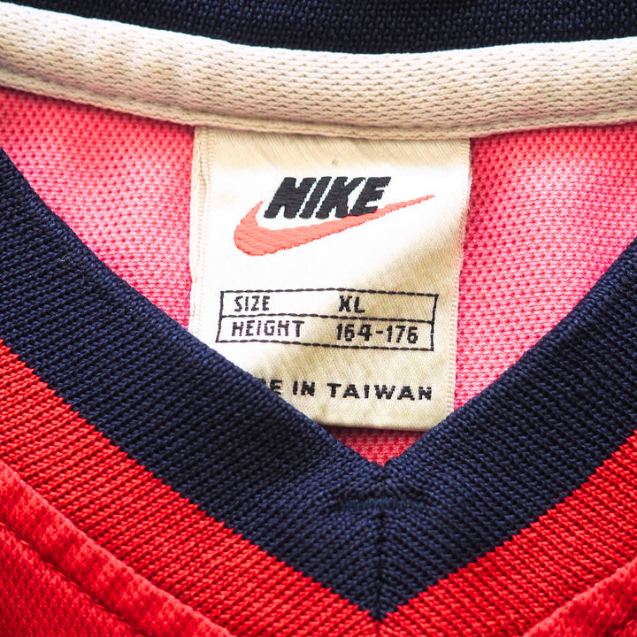 Close-up of a vintage Nike label on a red and navy sports jersey.