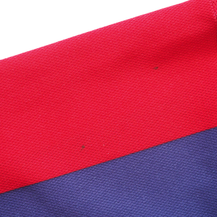 Close-up of red and blue fabric with a textured pattern and detailing two small spot stains on the red portion