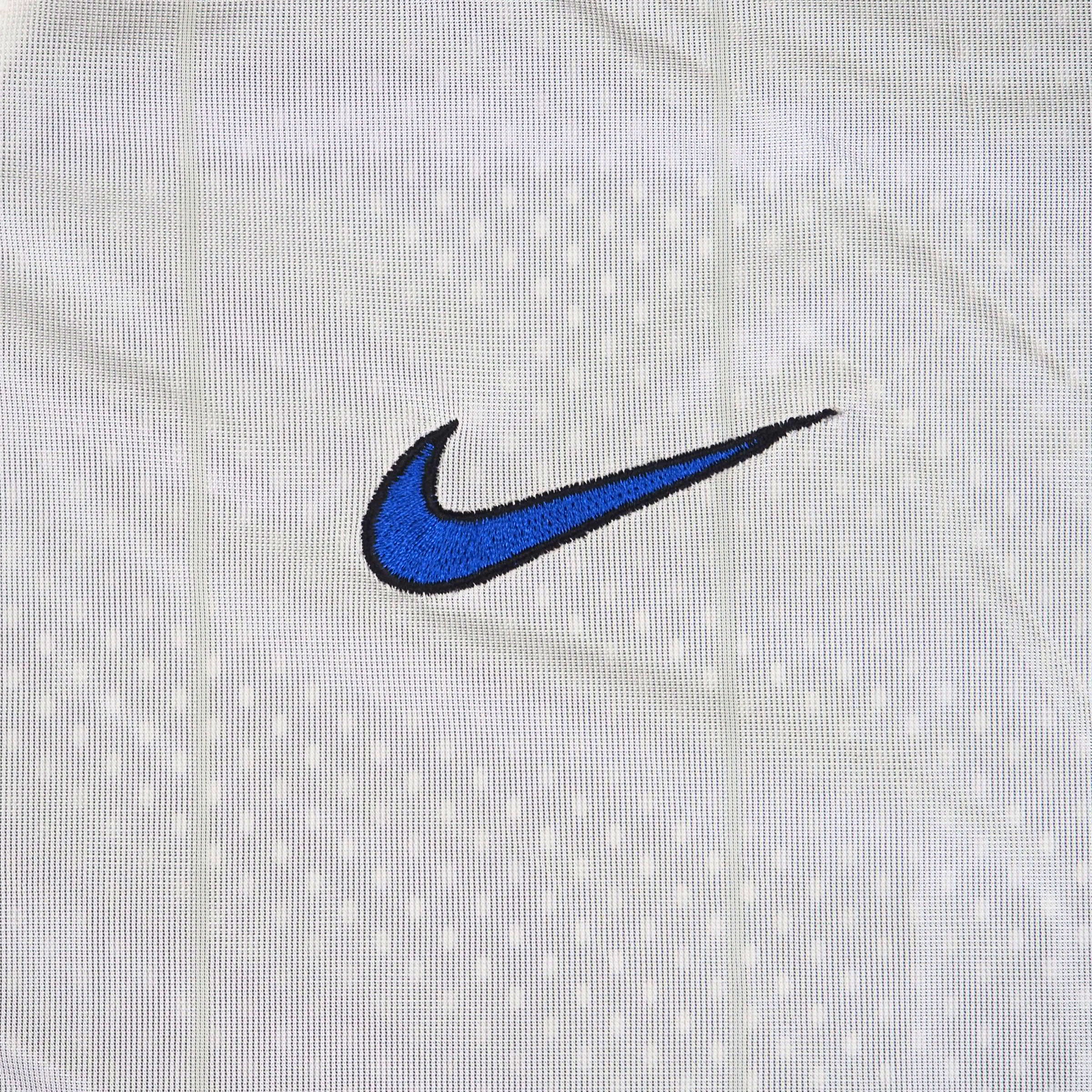 Close-up of a blue embroidered Nike swoosh logo on a white textured fabric background