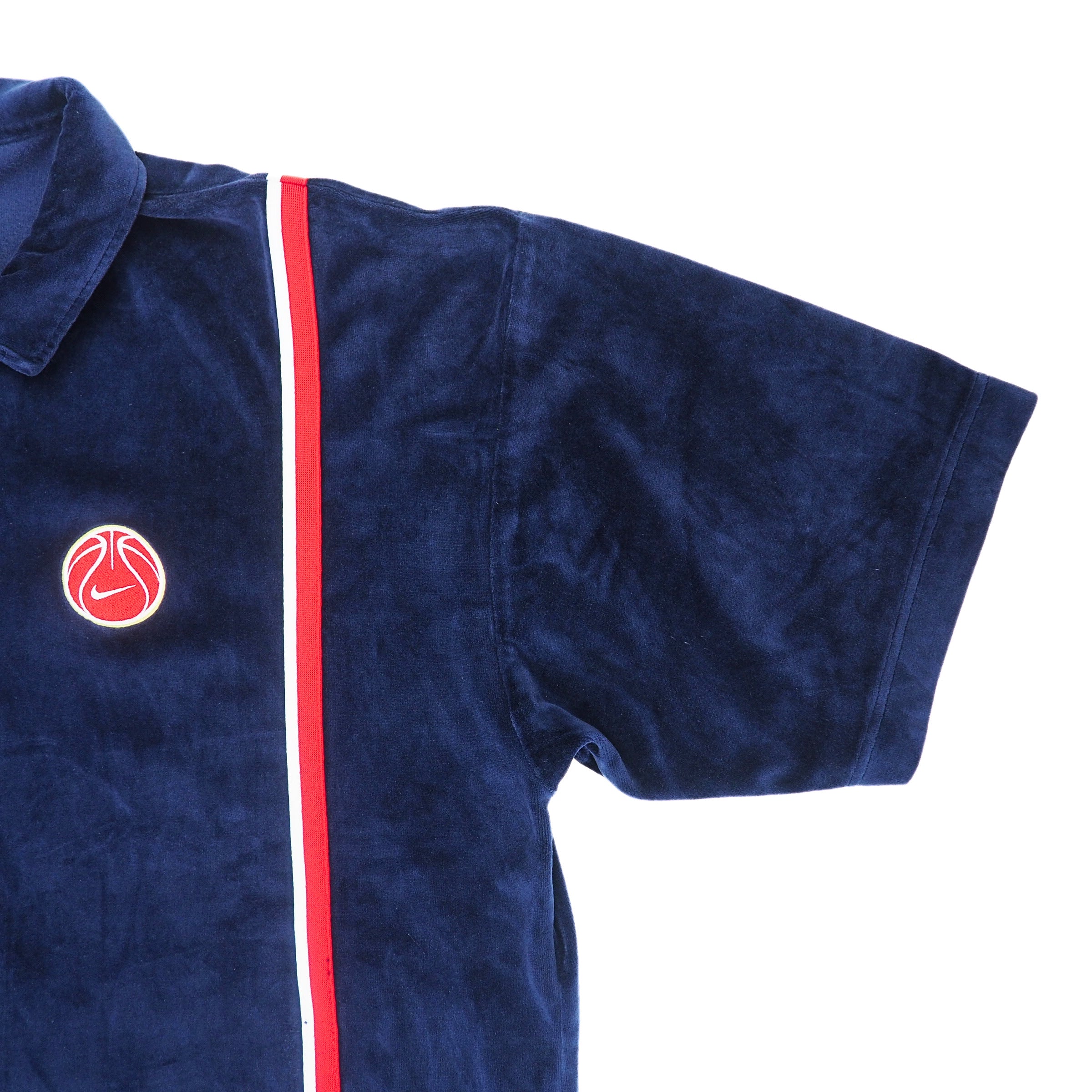 Left sleeve detail of a navy blue velour jacket with a red stripe and basketball logo