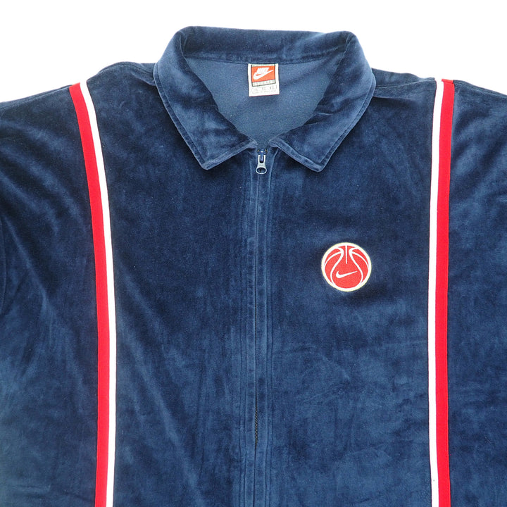 Detail of the chest and collar of a navy velour basketball jacket on a white background