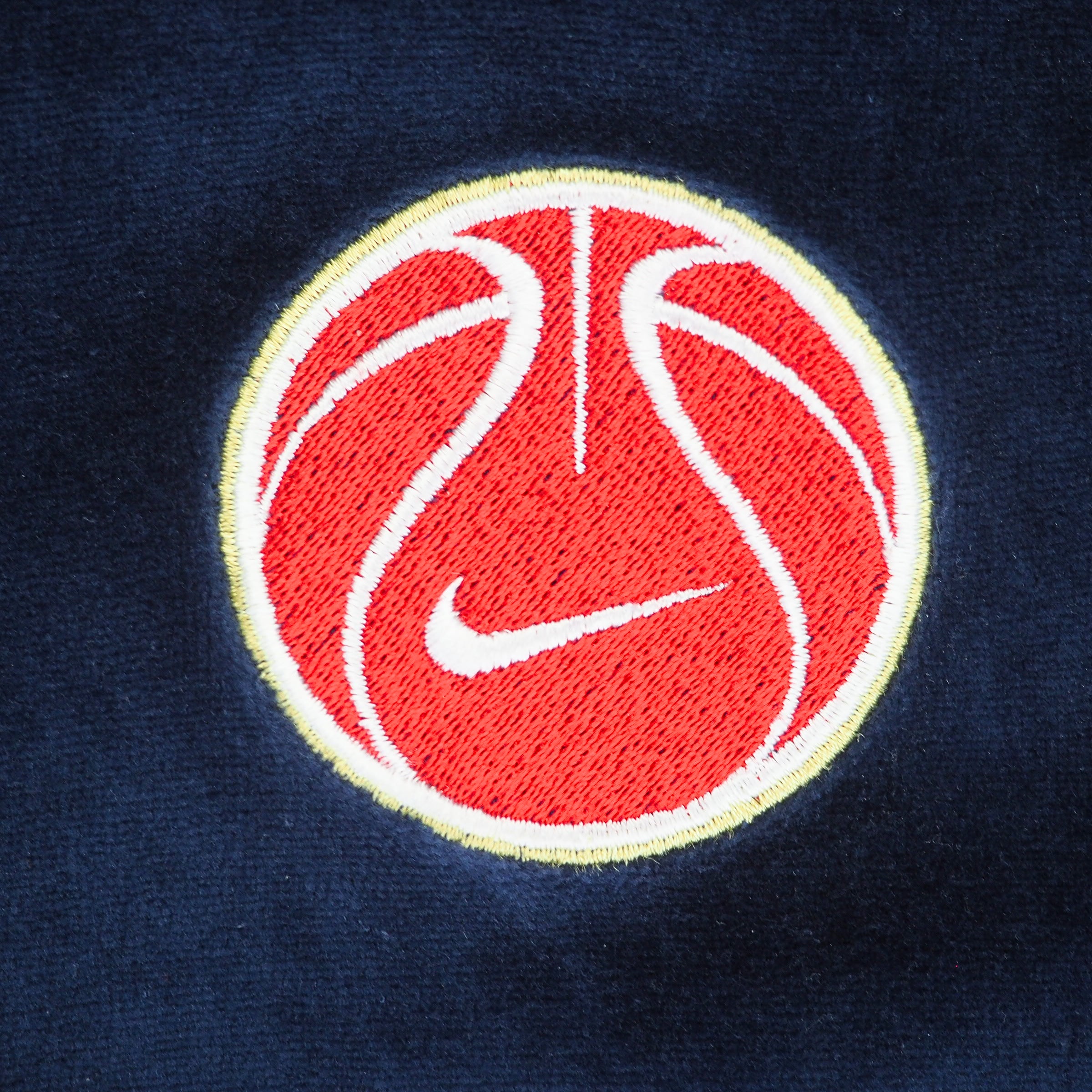 Close up of a red embroidered Nike Basketball patch on a blue velour jacket