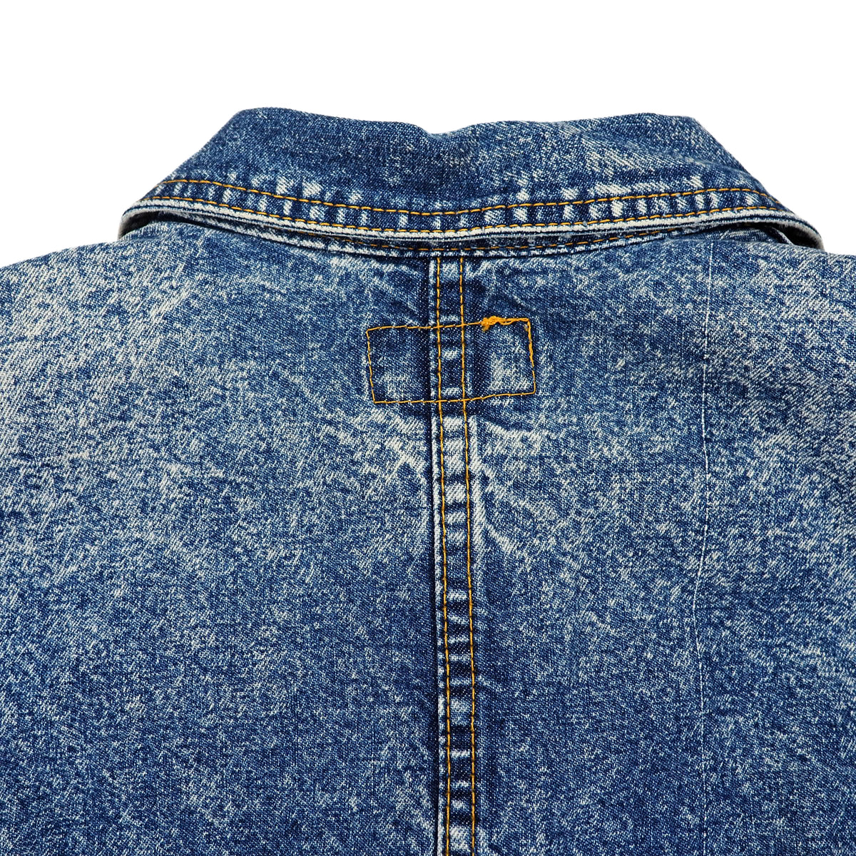 Close-up of the back of a blue denim jacket with a faded wash, showing the collar, center seam, and a rectangular stitching detail.