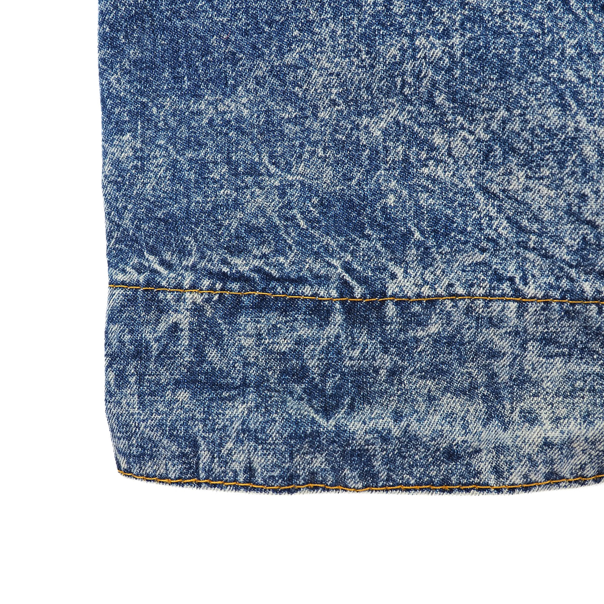 Close-up of a blue denim fabric detail showing a horizontal seam and orange contrast stitching on a white background.