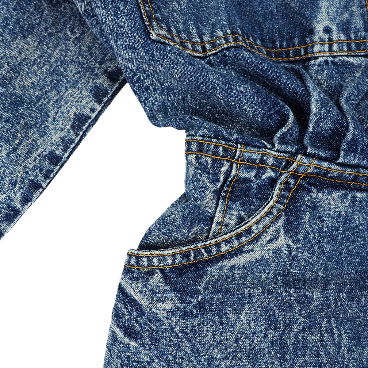 Close-up detail of a blue acid-wash denim garment, showing the textured fabric, orange contrast stitching, and pocket seams against a white background.