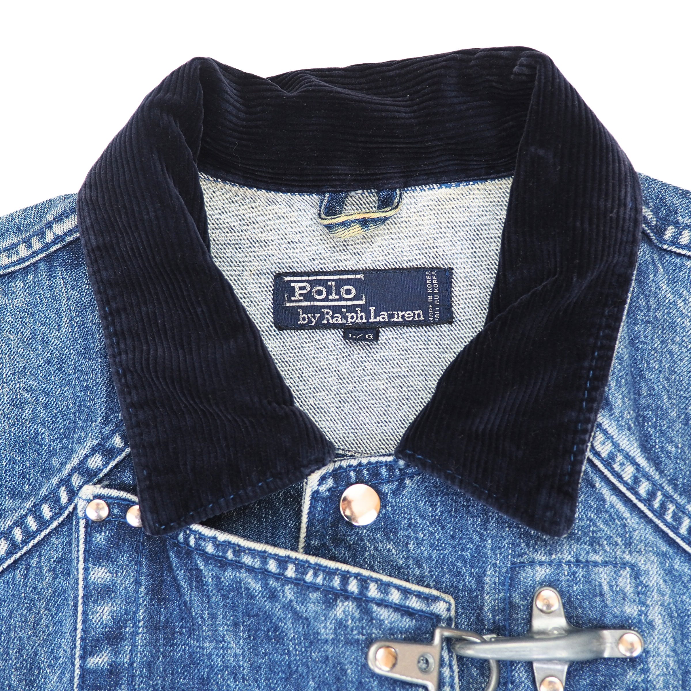 Close-up of a blue denim jacket with a dark navy corduroy collar and silver metal toggle closure, showing the Polo by Ralph Lauren neck label.