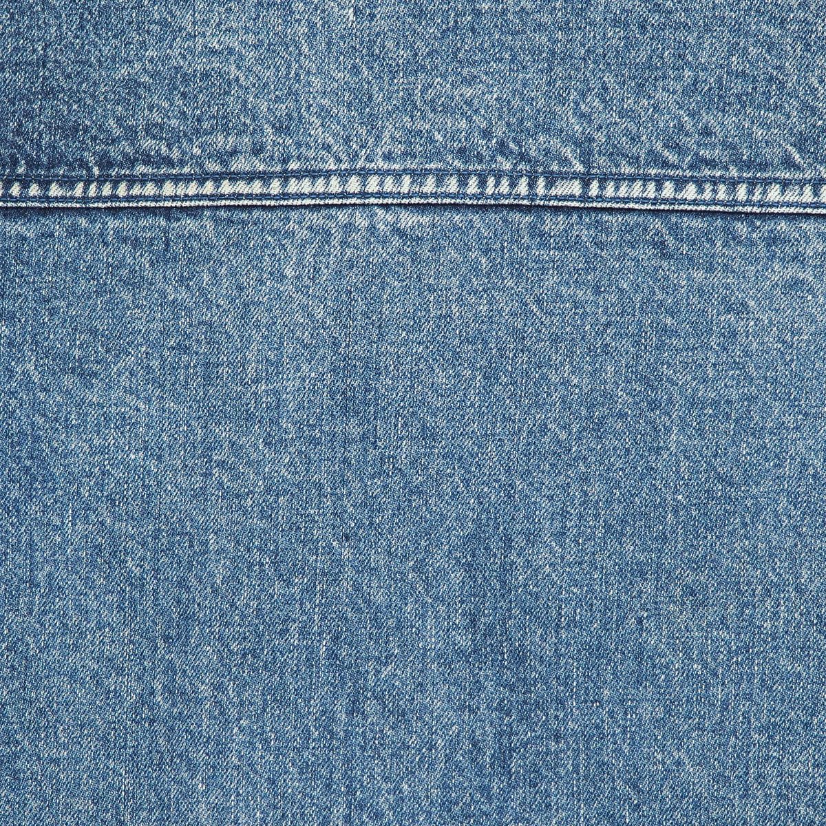 A close-up of blue denim fabric with a horizontal seam and visible weave texture.