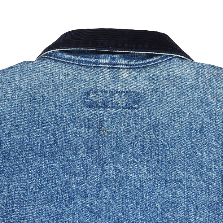 Close-up of the back of a blue denim jacket with a dark navy corduroy collar, showing a stitched brand label that reads 'SAS'.